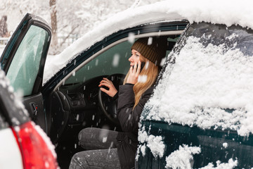 woman sitting in car on the phone in a snow storm